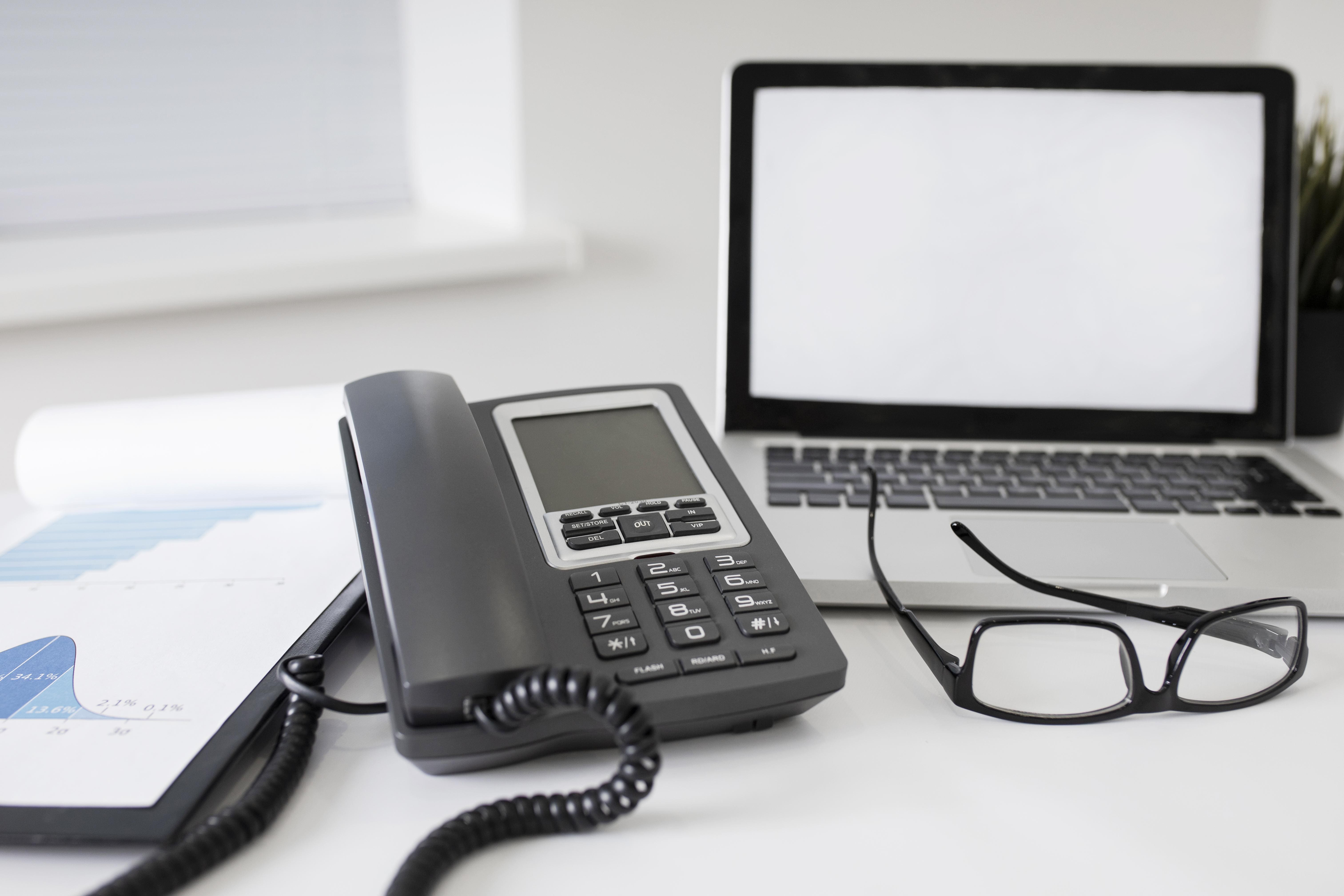 Poste de travail équipé d'un téléphone fixe et d'un ordinateur portable, illustrant la convergence fixe-mobile entreprise et l'unification des communications.