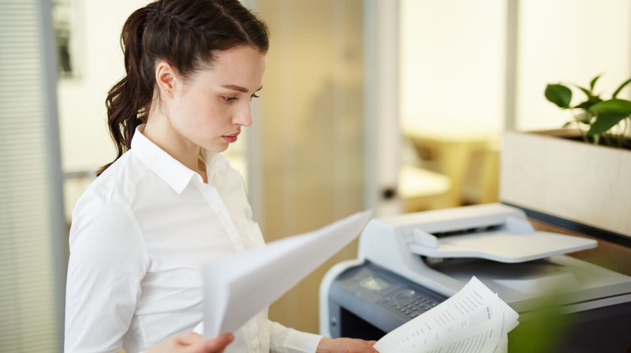 Une employée examine des documents imprimés avec une imprimante multifonction professionnelle 2026 dans un bureau.